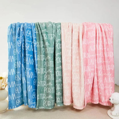 Assortiment de modèles de plaid personnalisé suspendus, affichant des prénoms en écriture blanche sur fonds bleu, vert sauge et rose.
