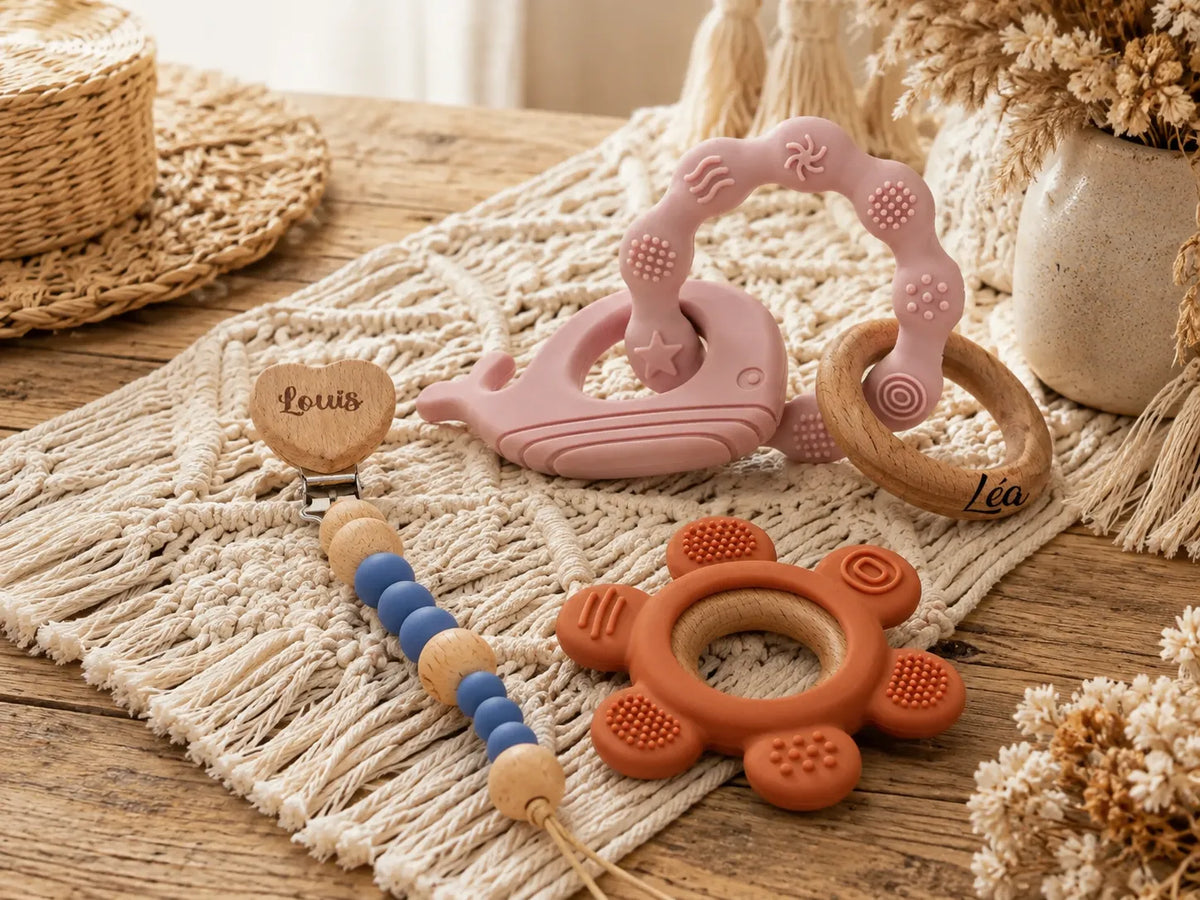 Cadeau personnalisé bébé avec prénom, attache tétine, anneaux de dentition et accessoires bébé personnalisés sur table en bois