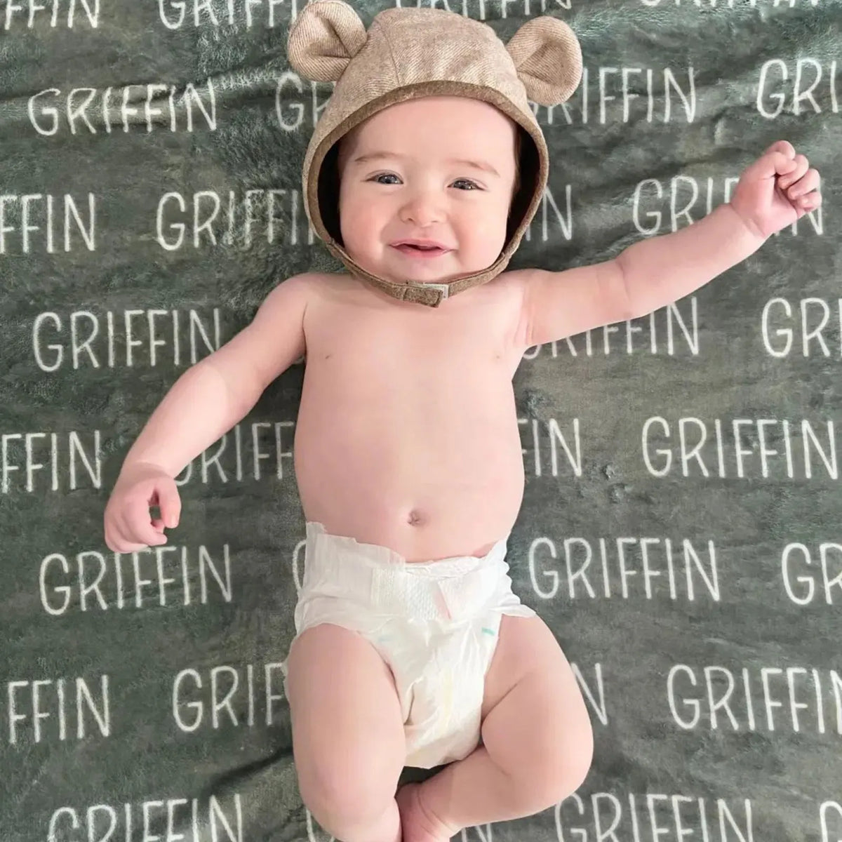 Plaid naissance personnalisé vert sapin avec prénom Griffin. Bébé avec bonnet ourson sur sa couverture douce en polaire. Idée cadeau garçon.